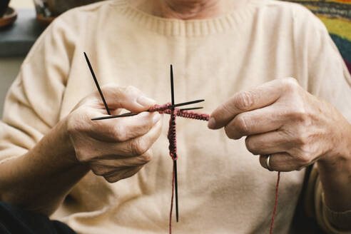 A serene elderly lady knitting at home with a steady hand, fully engrossed in her craft - MASF41159