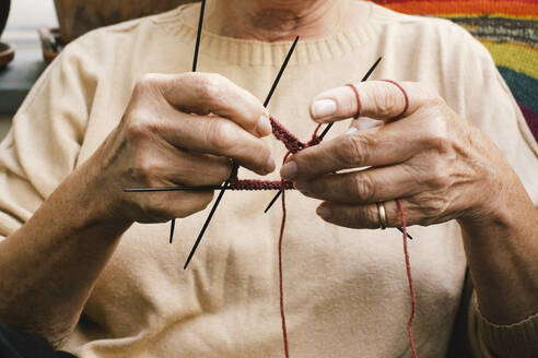 Eine zufriedene Seniorin widmet sich ihrem Strickhobby und entspannt sich in ihrem Zuhause. - MASF41160