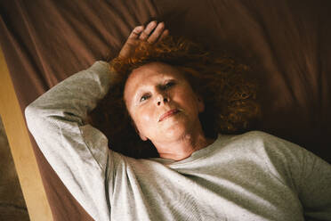 Eine ältere Frau denkt über das Leben nach, während sie sich zu Hause im Bett entspannt, aufgenommen aus der Vogelperspektive. - MASF41186