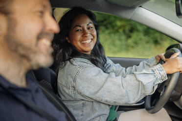 Eine fröhliche Frau wirft während der Fahrt einen Blick auf ihren Beifahrer - MASF41233