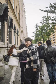 Eine Gruppe von Freunden im Teenageralter geht die Straße entlang, mit einem glücklichen Jungen im Vordergrund. - MASF41253