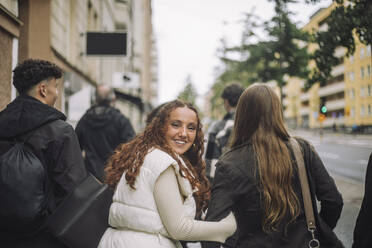 Portrait of smiling girl walking with teenage friends at street - MASF41254