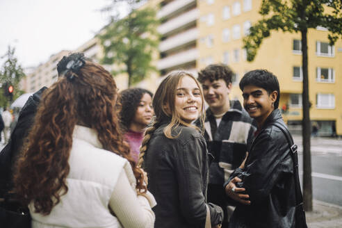 Portrait of smiling girl standing with male and female friends at street - MASF41257