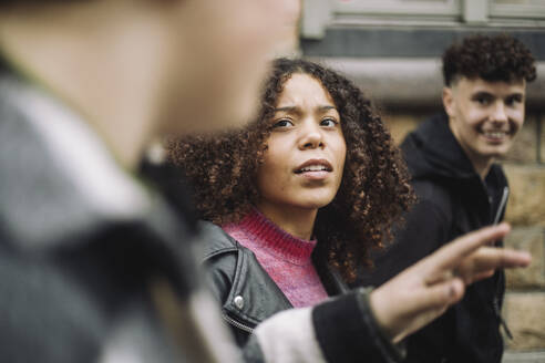 Zwei Freunde plaudern, während sie die Straße entlangschlendern - ein Mädchen im Teenageralter und ihr männlicher Begleiter - MASF41261