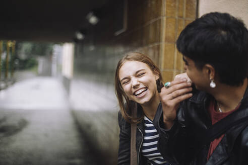 Two friends share a joyful moment as they laugh together against a colorful wall - MASF41278