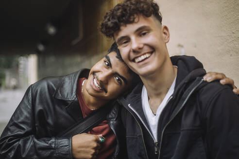 Zwei Freunde posieren für ein Foto, wobei sich ein Junge mit Lederjacke und einem breiten Lächeln an seinen männlichen Freund lehnt - MASF41280