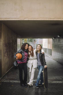 Smiling teenage girls standing together near underpass - MASF41282