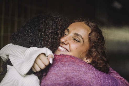 Two happy teenage girls sharing a warm embrace with closed eyes and bright smiles - MASF41283