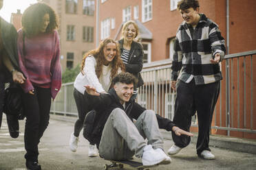 Joyful group of friends enjoying themselves while playing on the sidewalk - MASF41308