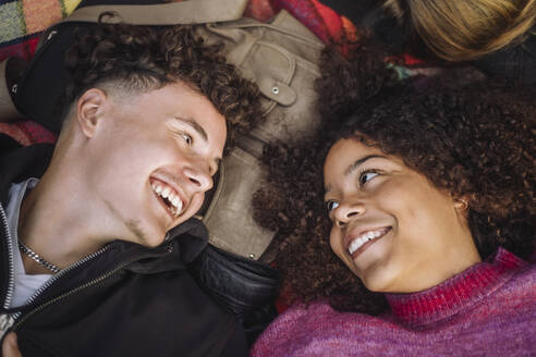 Cheerful teenage friends enjoying each other's company while lounging in the park - MASF41325