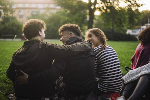 Zwei Freunde genießen die Gesellschaft des anderen, während sie in einem Park sitzen und sich umarmen. - MASF41328