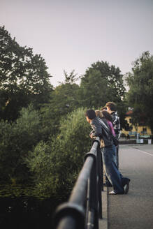 Freunde im Teenageralter genießen die Aussicht, während sie sich auf das Brückengeländer stützen, mit einer Mischung aus männlicher und weiblicher Gesellschaft - MASF41341