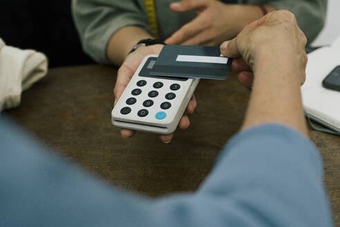 Kunde, der im Geschäft mit seiner Kreditkarte über das Tap-to-Pay-Verfahren bezahlt - MASF41359
