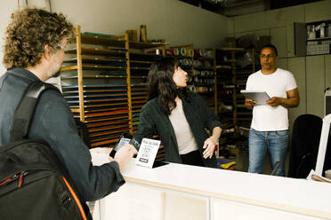 A customer picks up their repaired laptop from the repair shop. - MASF41393