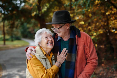 Romantic senior couple enjoying a leisurely stroll through the park, deeply in love - HPIF31648
