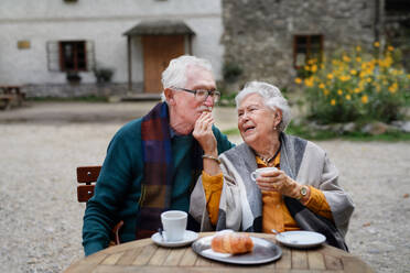 Älteres Ehepaar genießt Kaffee und Dessert in der Sonne in einem Straßencafé - HPIF31692