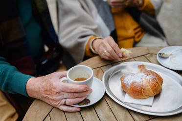 Nahaufnahme eines älteren Ehepaars, das in einem Straßencafé Kaffee und Kuchen genießt - HPIF31693