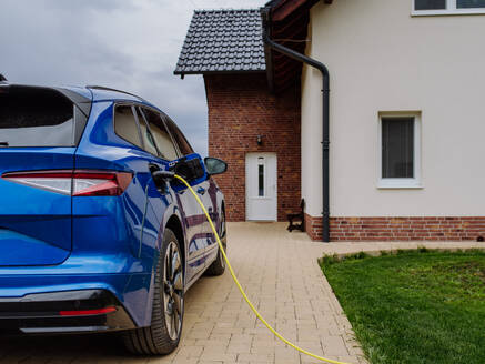 Close-up of electric car charging near a family house. - HPIF31744