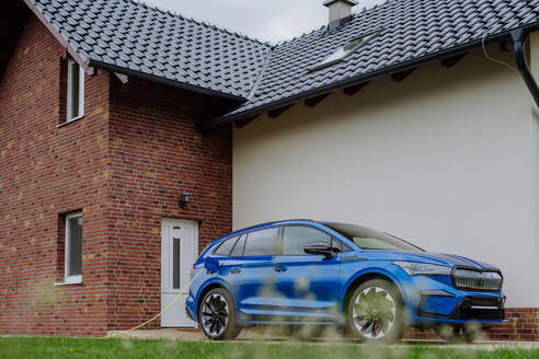 Close-up of electric car charging near a family house. - HPIF31755