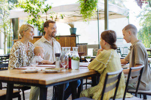 Ein fröhliches Familientreffen bei einem Abendessen in einem familienfreundlichen Restaurant, mit Kindern und einem kostbaren kleinen Baby - HPIF31775