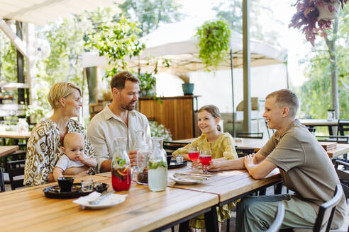 Ein fröhliches Familientreffen mit Kindern und einem Neugeborenen in einem gemütlichen Restaurant, perfekt für Familienfeiern - HPIF31780