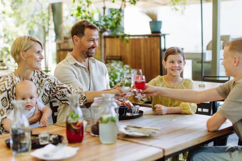 Ein fröhliches Familientreffen bei einer köstlichen Mahlzeit in einem familienfreundlichen Restaurant, mit Kindern und einem kostbaren Baby - HPIF31782