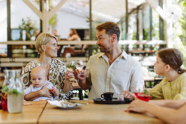 Ein fröhliches Familientreffen beim Abendessen in einem kinderfreundlichen Restaurant, mit Kindern und einem süßen kleinen Baby - HPIF31783