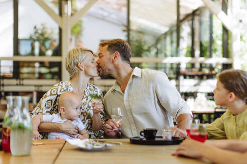 Eine glückliche vierköpfige Familie, die ein gemütliches Abendessen in einem familienfreundlichen Restaurant genießt, um einen besonderen Anlass zu feiern - HPIF31784