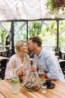 Ein romantischer Moment, als sich ein Paar auf der Terrasse eines Restaurants küsst, während es sich verabredet - HPIF31799