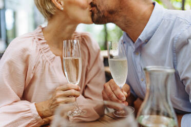 Ein Paar verbringt einen romantischen Moment beim Abendessen auf der Terrasse eines Restaurants, wobei sich die Frau und der Mann küssen - HPIF31800