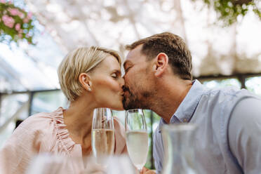 Ein Paar genießt einen romantischen Moment auf der Terrasse eines Restaurants, küsst sich und genießt die Gesellschaft des anderen bei einem Date - HPIF31802