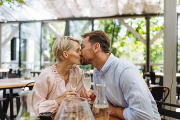Ein Paar genießt einen romantischen Moment auf der Terrasse eines Restaurants, küsst sich und genießt die Gesellschaft des anderen bei einem Date - HPIF31803