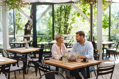 Ein verliebtes Paar, das einen romantischen Moment beim Abendessen auf einer gemütlichen Restaurantterrasse verbringt und sich inmitten der Atmosphäre küsst - HPIF31805