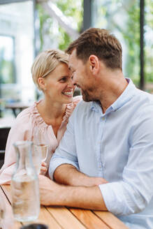 Romantisches Paar, das sich auf der Terrasse eines Restaurants verabredet und einen intimen Moment miteinander teilt, während sie ihre Stirne berühren - HPIF31808