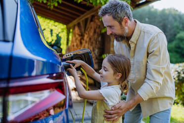Ein Vater und seine kleine Tochter laden ihr umweltfreundliches Elektroauto auf und setzen damit ein Zeichen für eine nachhaltige Zukunft - HPIF31826