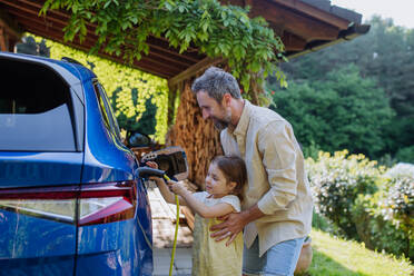 Ein Vater und seine kleine Tochter laden ihr Elektrofahrzeug auf und setzen damit ein Zeichen für eine nachhaltige Zukunft - HPIF31827