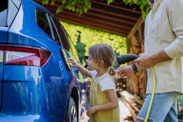 Ein Vater und seine kleine Tochter laden ihr umweltfreundliches Elektroauto auf und setzen damit ein Zeichen für eine nachhaltige Zukunft - HPIF31828