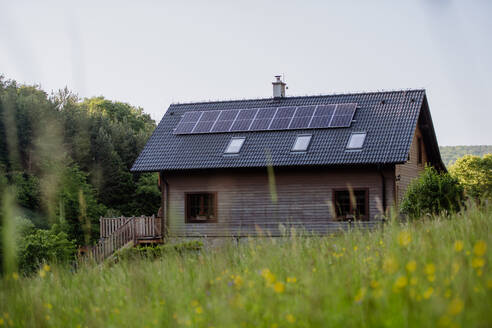 A sustainable family home with solar panels installed on the roof, nestled in a picturesque meadow - HPIF31841