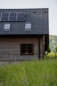 A sustainable family home with solar panels installed on the roof, nestled in a picturesque meadow - HPIF31842