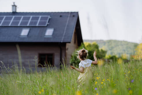 Ein junges Mädchen steht vor dem solarbetriebenen Haus ihrer Familie und wirbt für nachhaltiges Leben und erneuerbare Energien. - HPIF31844