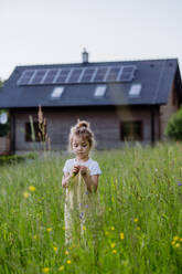 Ein junges Mädchen steht stolz vor dem solarbetriebenen Haus ihrer Familie und wirbt für einen nachhaltigen und umweltfreundlichen Lebensstil. - HPIF31847