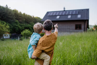 Father and son admiring their solar-powered home from behind - HPIF31851