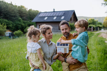 Eine zufriedene Familie posiert vor ihrem mit Solarenergie betriebenen Haus und ist stolz auf ihre Entscheidung für nachhaltige Energie - HPIF31861