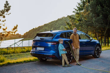 Vater und Sohn laden ihr Elektroauto auf einer Autoreise auf und reduzieren so ihren CO2-Fußabdruck und sparen Geld für Kraftstoff - HPIF31863