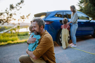 Eine vierköpfige Familie lädt ihr Elektroauto während einer Autofahrt auf - HPIF31865