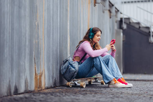 Portrait of generation z girl student sitting outdoors in the city. Student spending free time online and alone. Concept of gen Z as loneliest generation. - HPIF31878