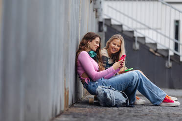 Young stylish generation Z girls spending time outdoors after school. Young female zoomers talking and gossiping during lunch break in the school. Concept of power of friendship and importance of education for gen Z. - HPIF31879