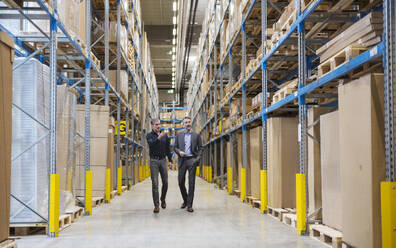 Businessmen walking and discussing in warehouse - DIGF21003