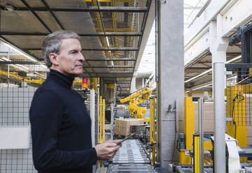 Manager bedient Maschinen mit Tablet-PC in der Fabrik - DIGF21012