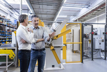 Businessman discussing with colleague in factory - DIGF21015